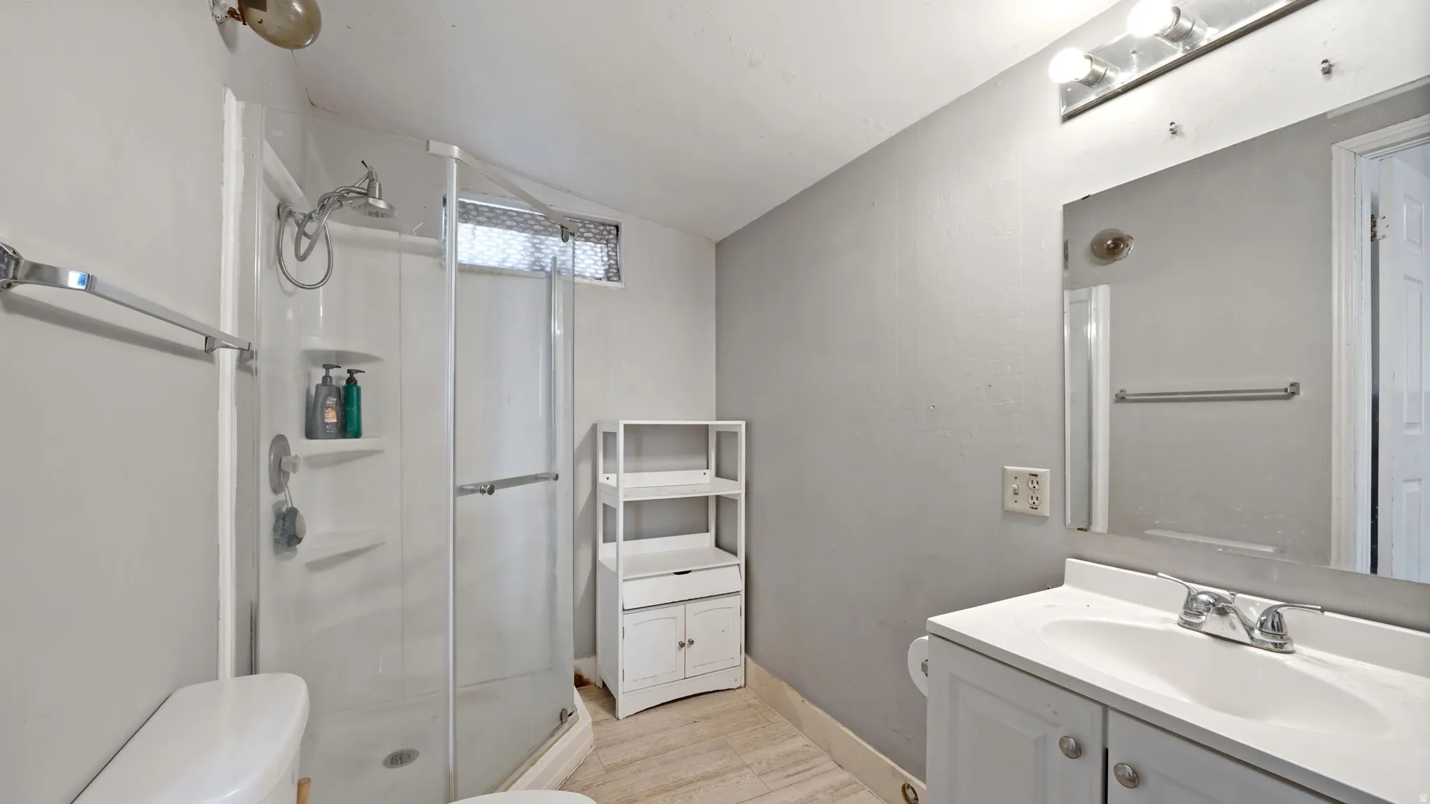 Primary Bathroom featuring a built-in shower enclosure with a glass door, a vanity with an integrated sink, a wall-mounted mirror, and overhead lighting