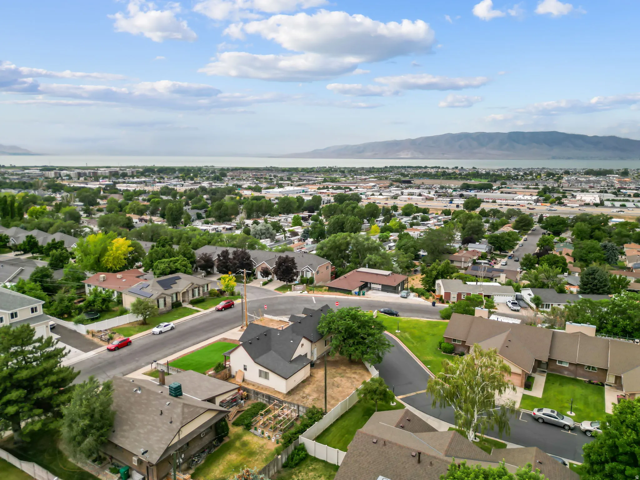 Expansive aerial perspective showcasing a residential neighborhood with distant body of water and mountain range