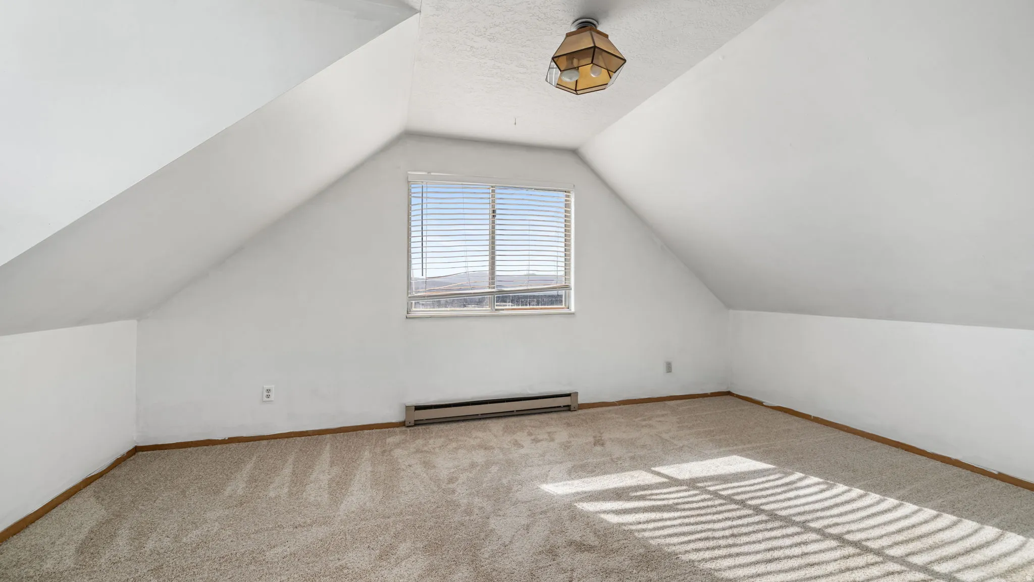 Carpeted room featuring a ceiling-mounted light fixture, window with blinds, and sloped ceiling