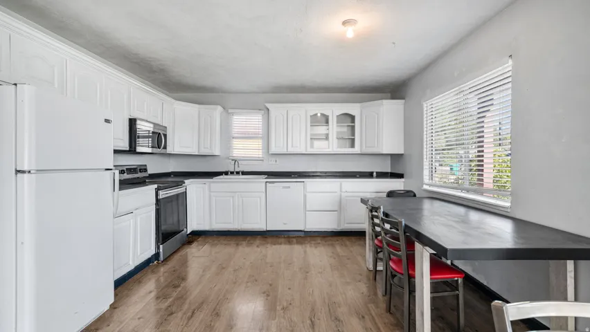 Kitchen featuring white cabinetry, dark countertops, wood-finish flooring, and a large window