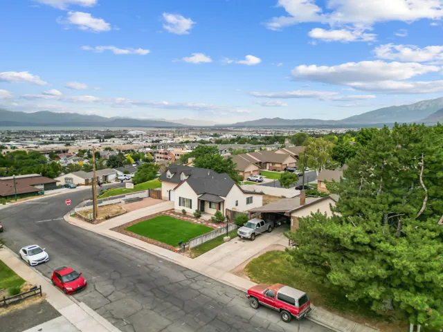 Elevated property featuring a light-toned exterior with dark roofing and a neatly maintained front lawn