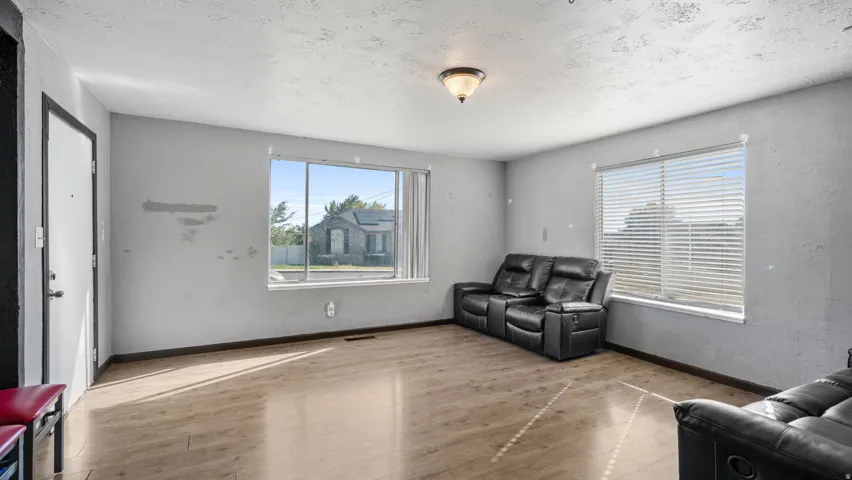 Wood-finish flooring with dual windows featuring blinds and a flush-mount ceiling light