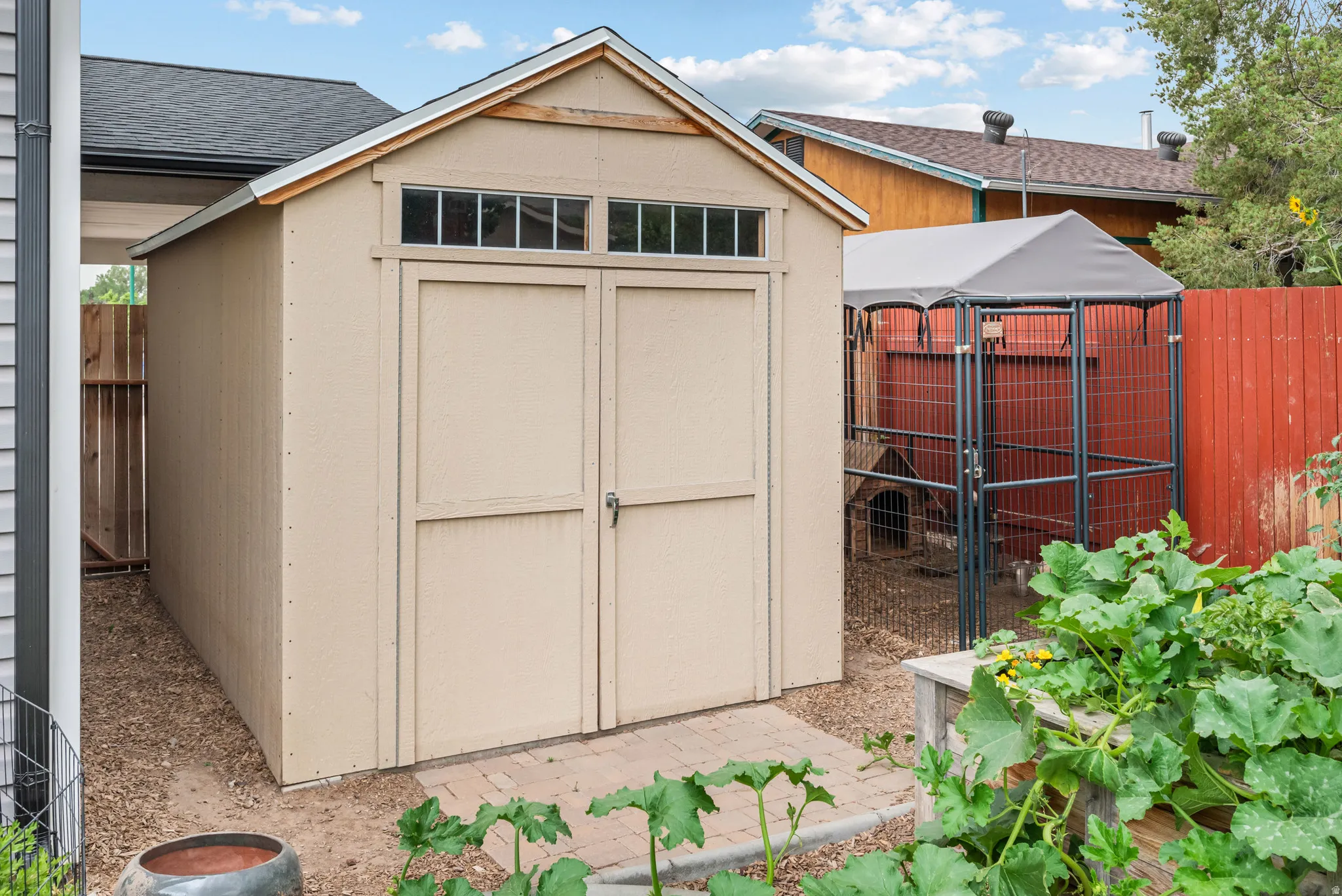 Freestanding outdoor storage shed featuring a gable roof and transom windows above double doors