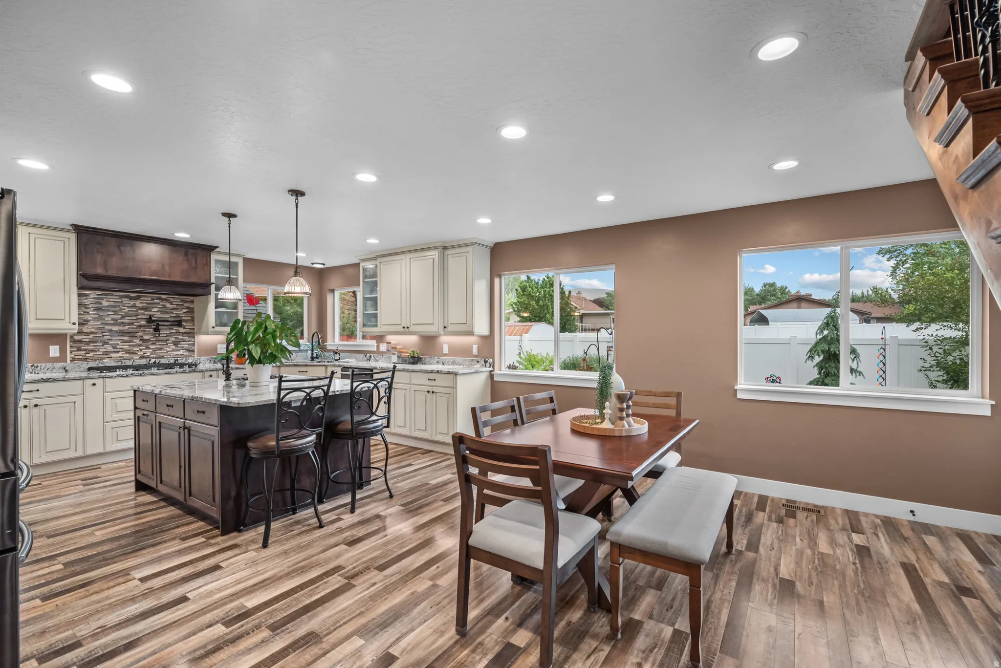 Open-concept kitchen featuring an island with stone countertop, stainless steel appliances, and wood-finish flooring