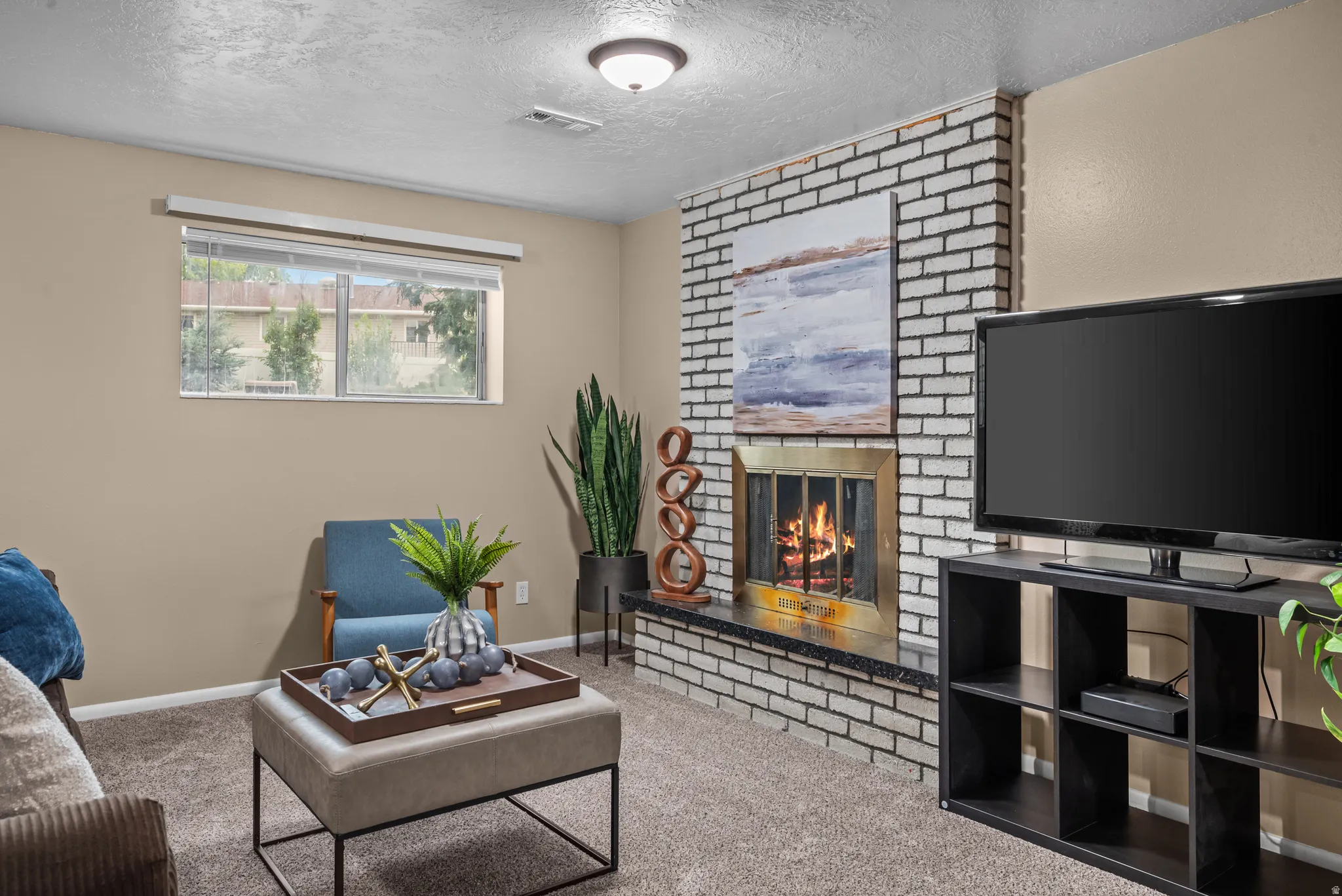Living area featuring a brick fireplace with a brass firebox, a black granite hearth, and neutral carpeting