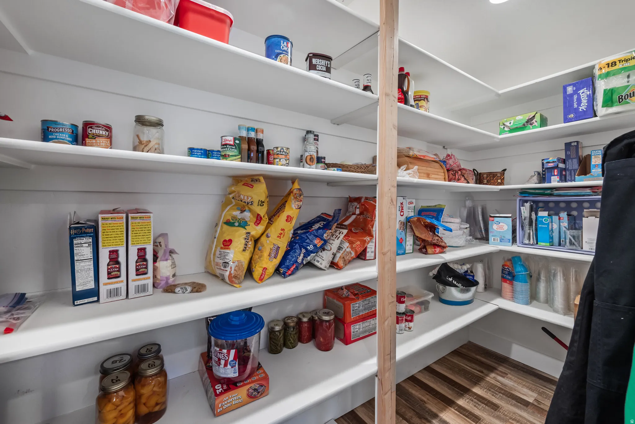 Walk-in pantry featuring extensive white shelving, wood-finish flooring, and recessed ceiling lighting