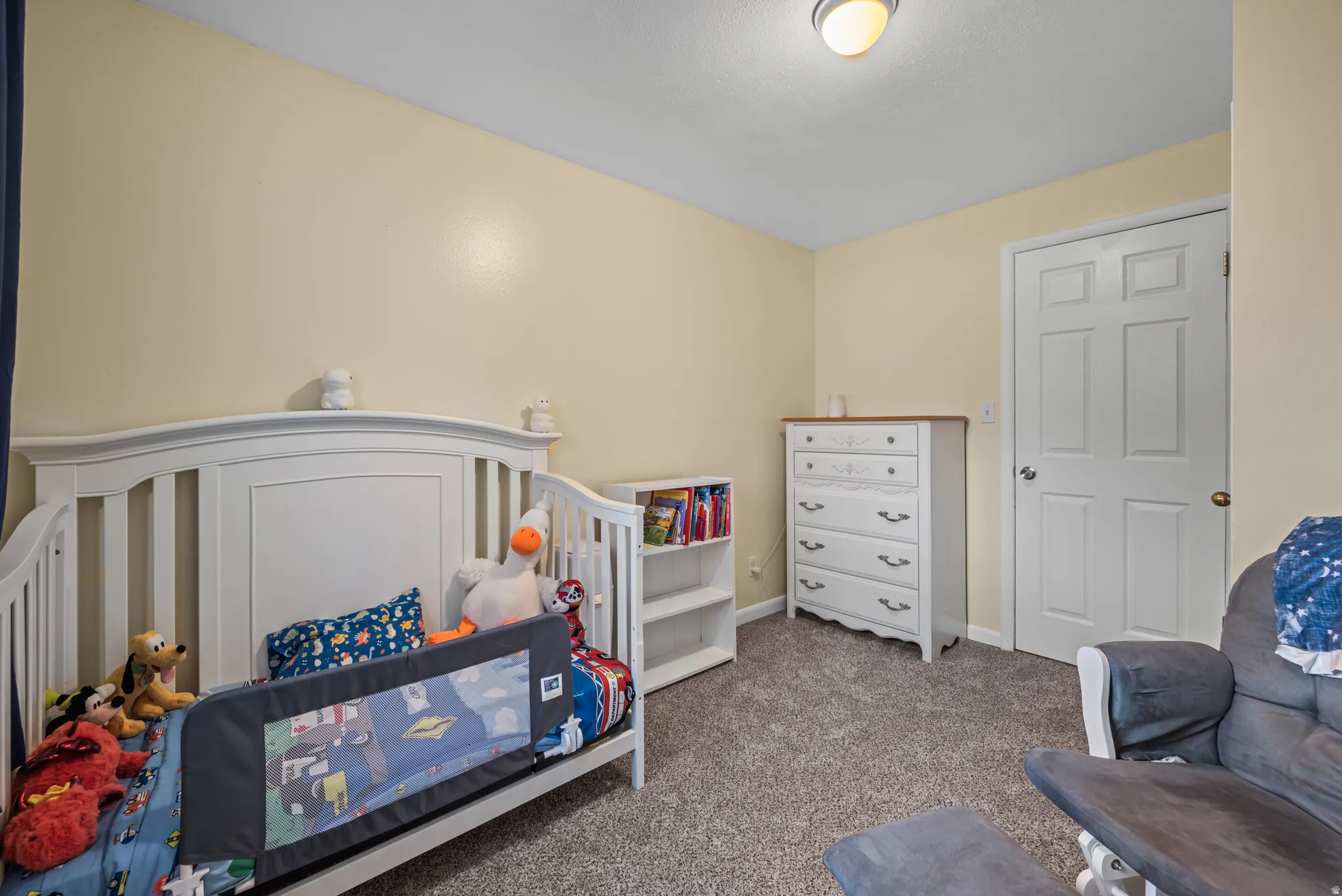 Bedroom featuring light-colored walls, carpeted flooring, a white paneled door, and a flush mount ceiling light fixture