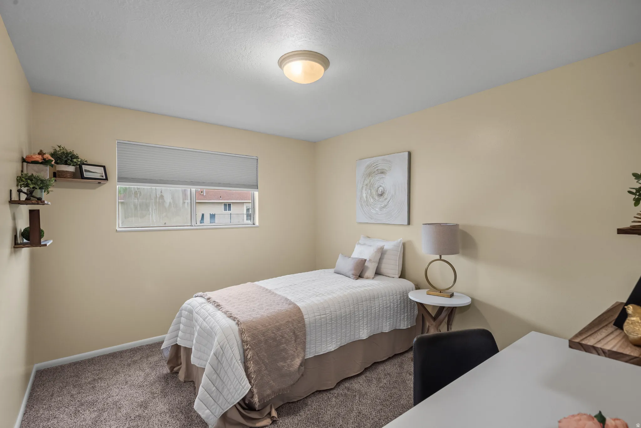 Carpeted interior room featuring a single window with blinds, a flush-mount ceiling light, and wall-mounted shelving