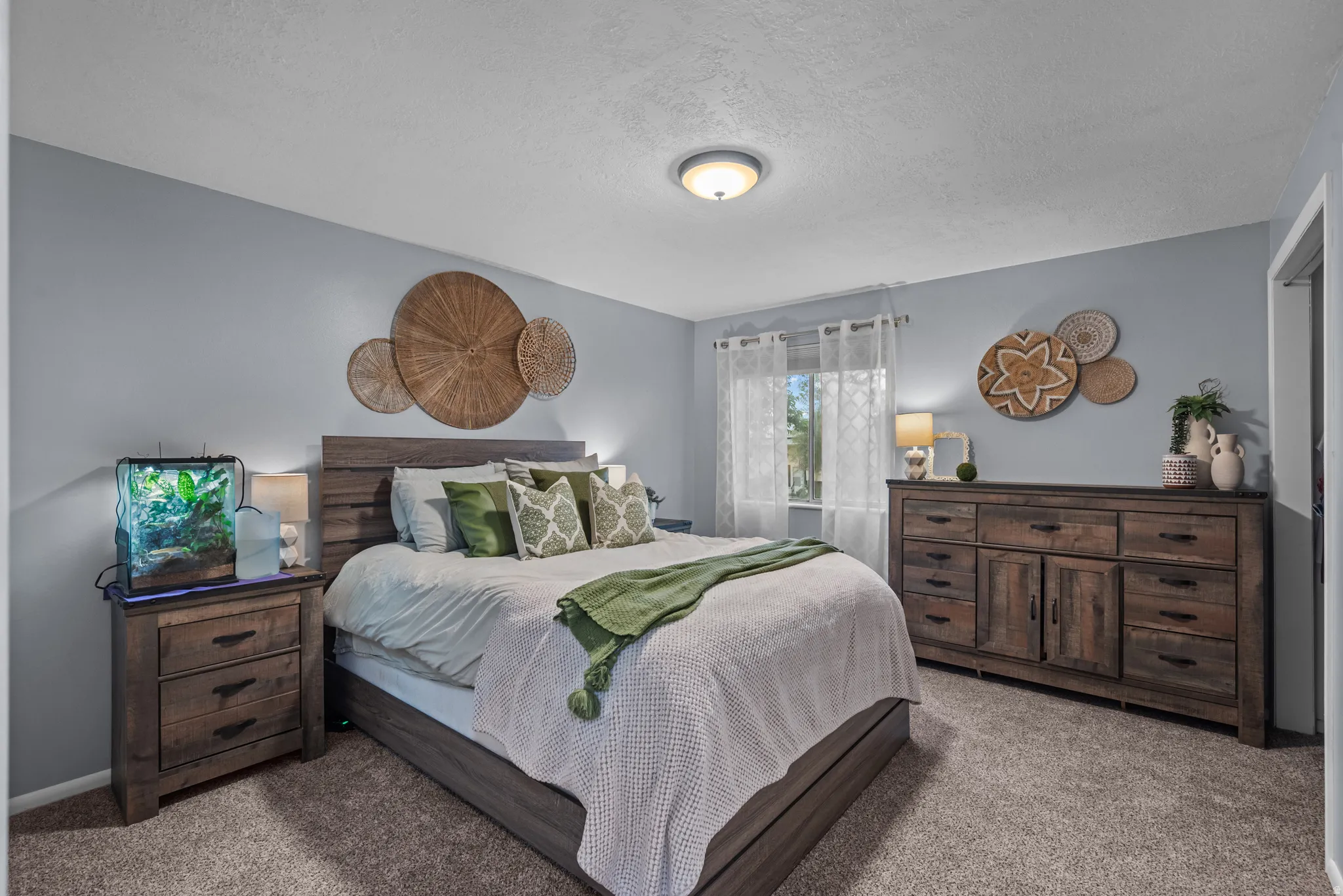 Spacious bedroom featuring light gray painted walls and neutral carpet flooring