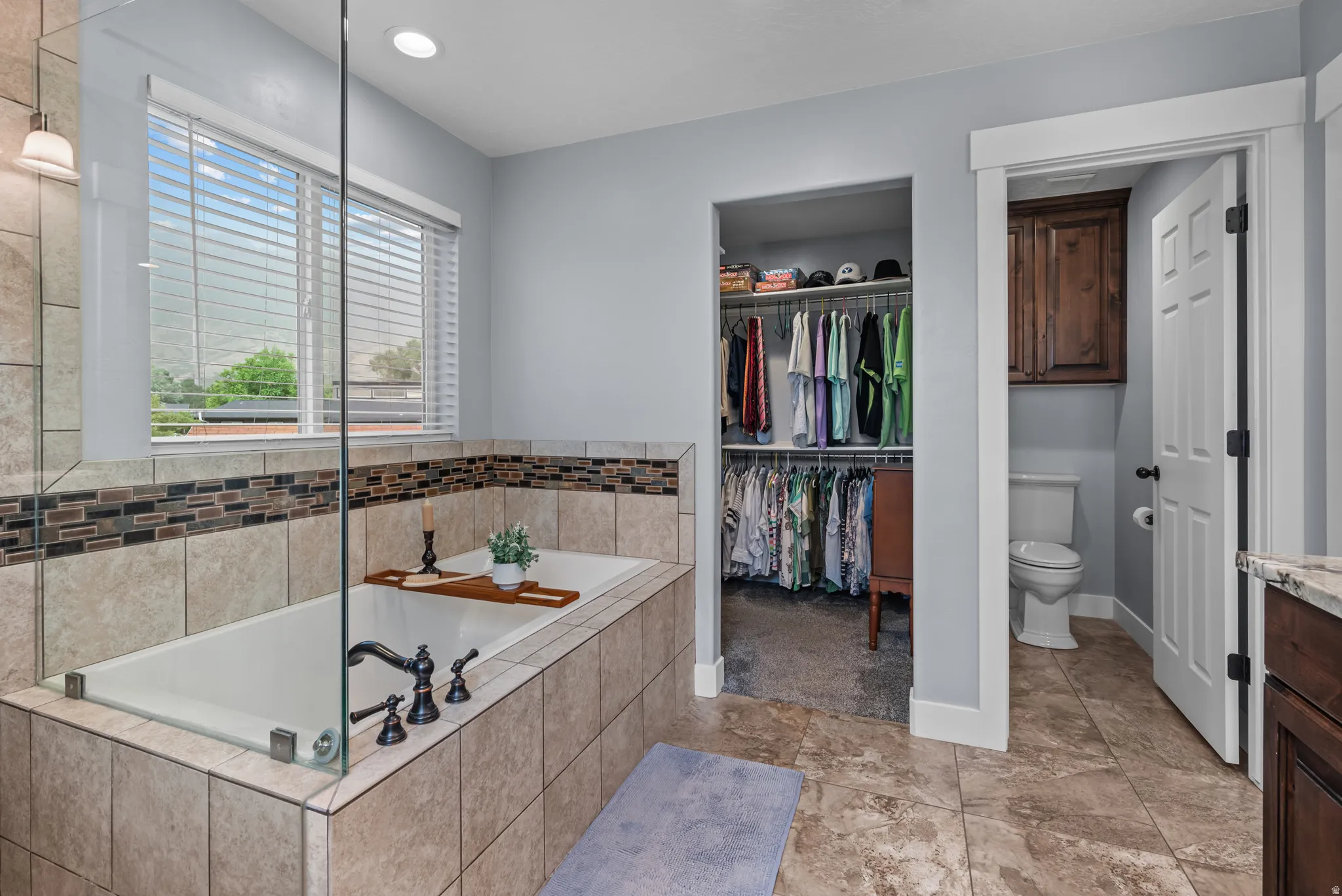 Built-in soaking tub with tile surround, glass shower enclosure, and dark bronze fixtures