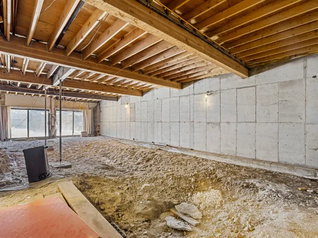 Exposed wood joist ceiling and concrete panel walls define this spacious area