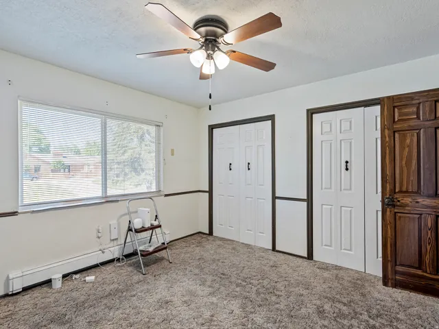 White walls with dark trim, featuring two sets of white bifold doors and a natural wood-finish panel door