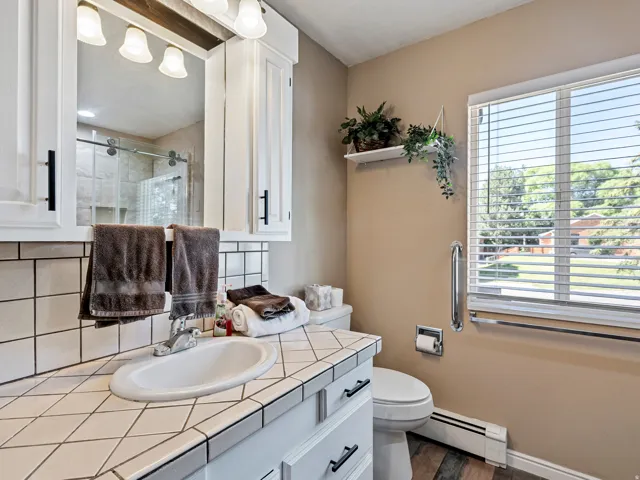 Bathroom vanity featuring a tiled countertop, white oval sink, and chrome faucet