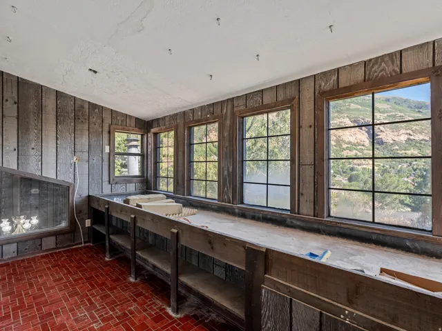 Room featuring wood-paneled walls, multiple grid-pane windows with mountain scenery, and a red brick-patterned floor