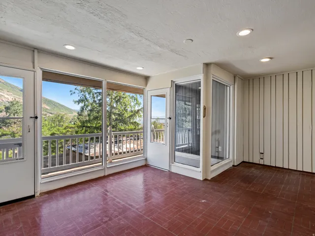 Sunroom featuring expansive windows, brick-patterned flooring, a white railing, and recessed ceiling lighting