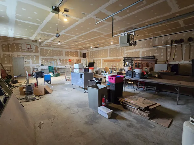 Spacious utility building featuring a concrete floor, exposed drywall with tape and mudding, and overhead lighting