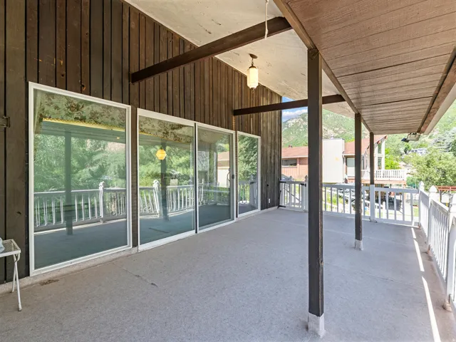 Expansive covered patio featuring a textured concrete surface, white spindle railing, and multiple sliding glass doors