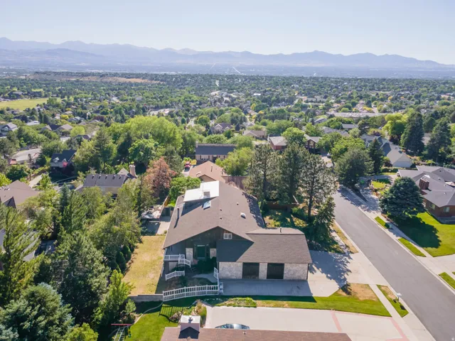 Aerial perspective showcasing the property's roofline, front driveway with a two-car garage, and surrounding green landscaping