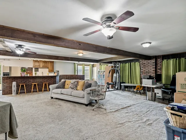 Spacious room featuring exposed wood beams and brick accent walls