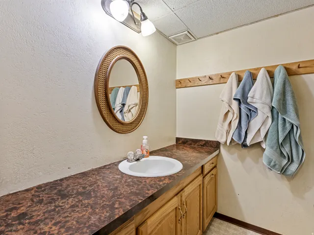 Bathroom vanity featuring a white oval sink, wood-finish cabinetry, and a patterned countertop