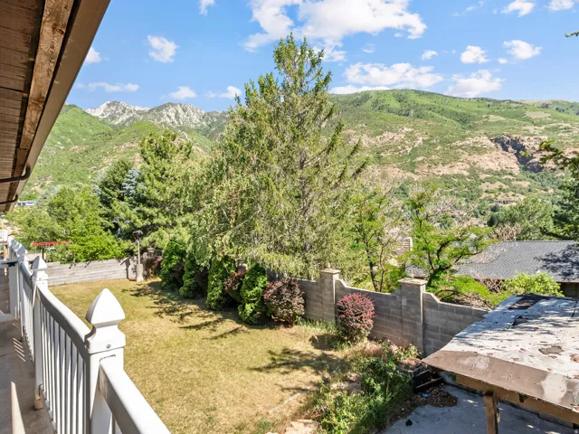 Expansive backyard featuring a manicured lawn, established landscaping, and a sturdy block retaining wall