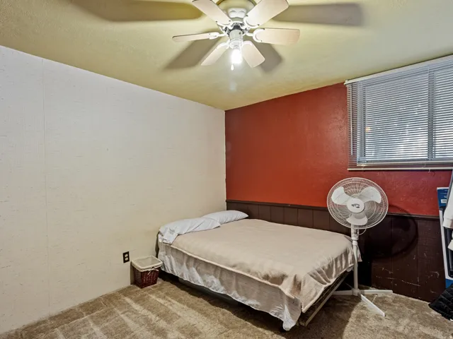 Bedroom featuring carpet flooring, a ceiling fan with integrated lighting, and a window with blinds