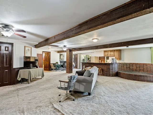 Expansive open-concept room featuring exposed wood ceiling beams, a brick-front bar area, and a built-in brick-faced hearth