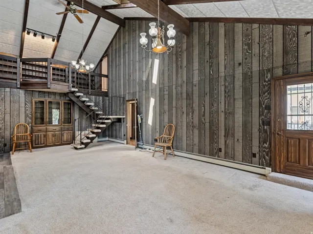 Vaulted ceiling living space featuring a wood-paneled accent wall, open loft area, and a spiral staircase