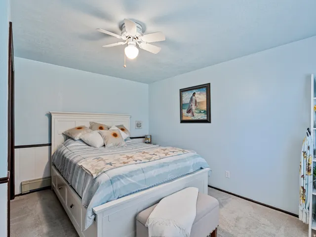 Room featuring light blue walls, a white ceiling fan with integrated lighting, and light-toned carpeting