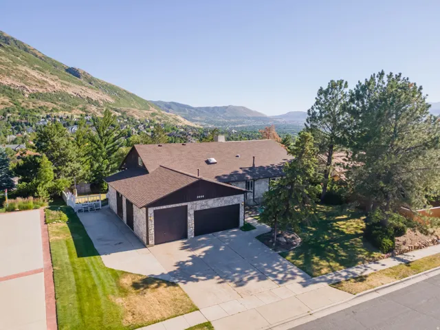 Expansive residence featuring a stone and wood exterior, multi-car garage, and a brown shingle roof