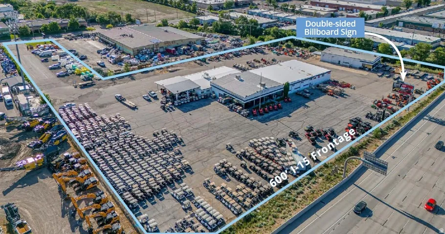 Expansive commercial property featuring multiple buildings, extensive paved and unpaved lot space, and a billboard sign