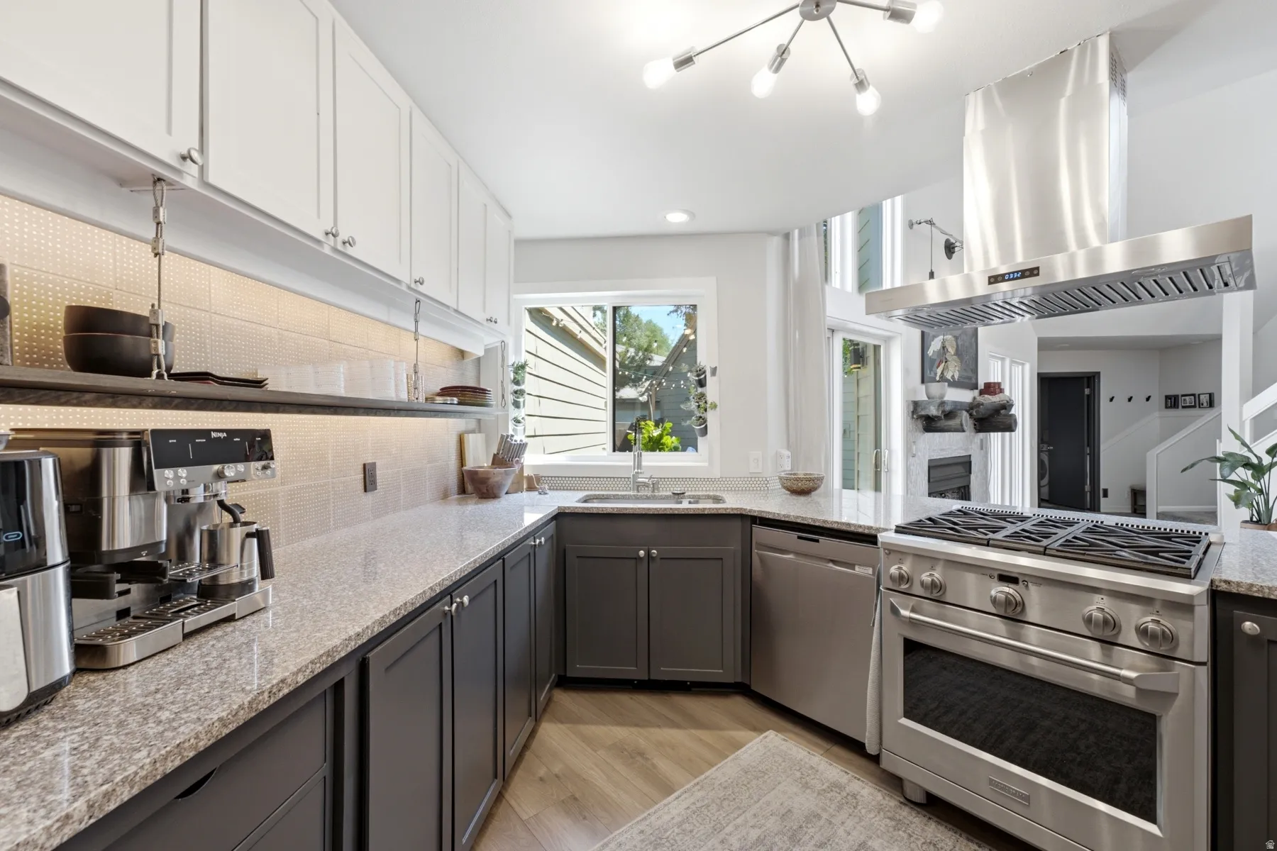 Modern kitchen featuring white upper cabinetry and grey lower cabinetry, granite countertops, a stainless steel range with matching ventilation hood, and wood-finish flooring
