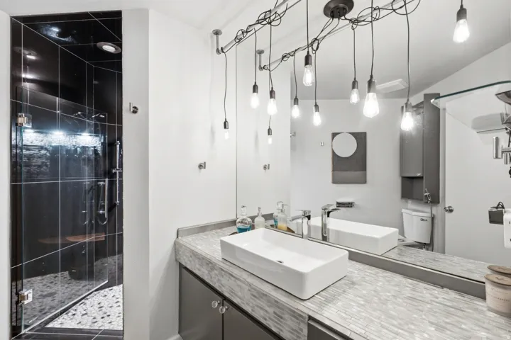 Contemporary bathroom featuring a spacious glass-enclosed shower with dark tile and pebble flooring