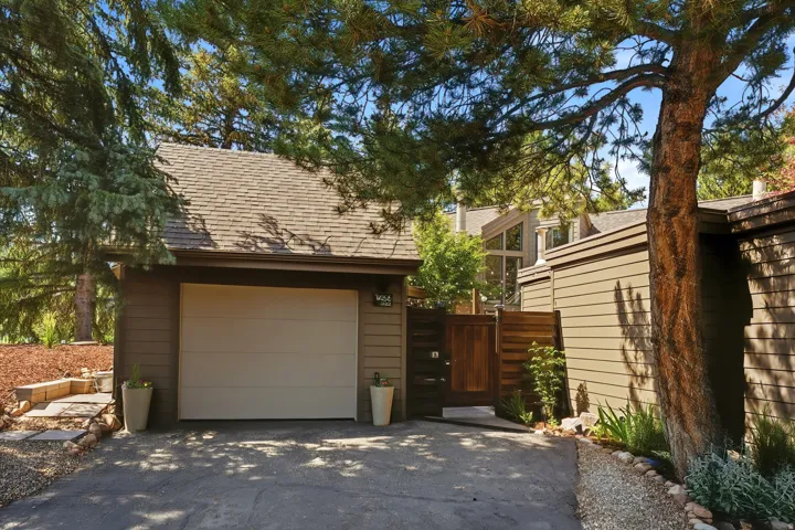 Attached garage with a tan overhead door, flanked by a privacy fence and a paved driveway