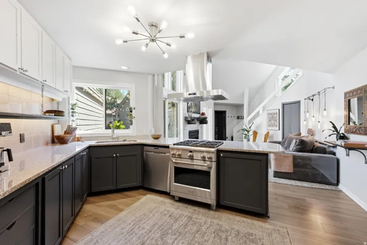 Modern kitchen featuring stainless steel appliances, granite countertops, two-tone cabinetry, wood-finish flooring, and a contemporary ceiling light fixture