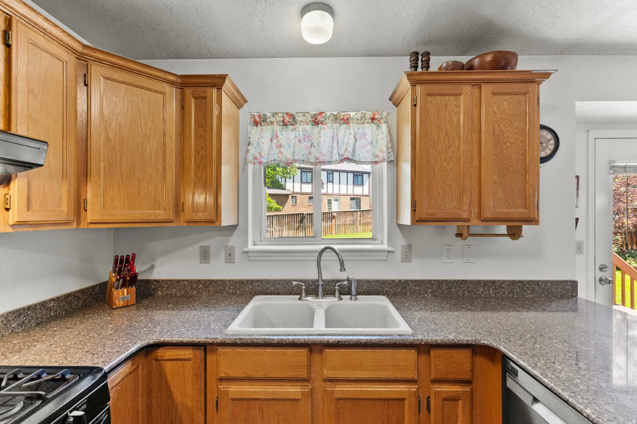 Kitchen featuring wood cabinetry, speckled countertops, and a double basin sink with a chrome faucet