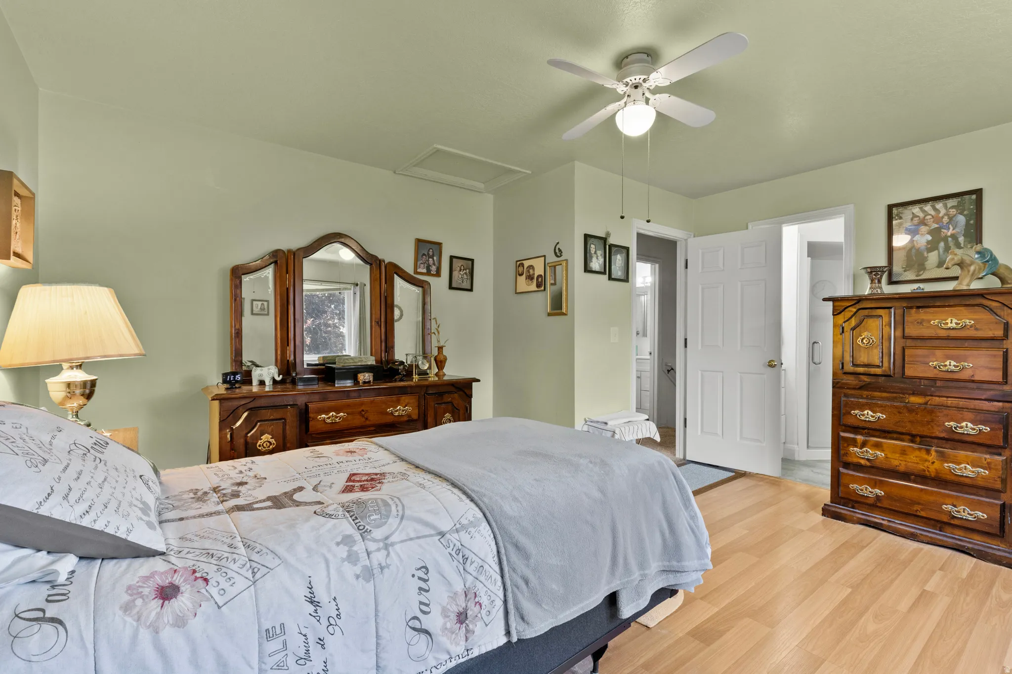 Bedroom featuring light green walls, wood-finish flooring, and a ceiling fan with integrated lighting