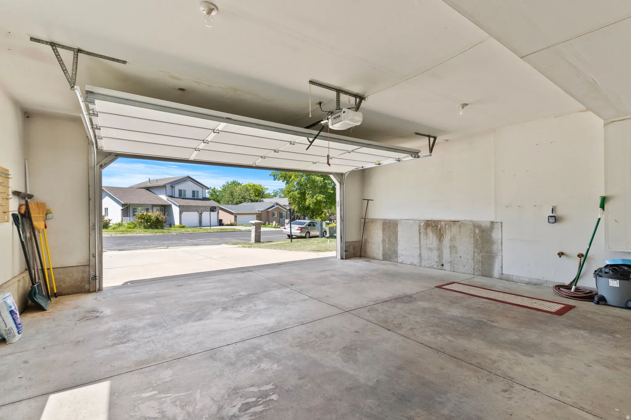 Spacious garage with concrete flooring, automatic overhead door, and exposed concrete foundation