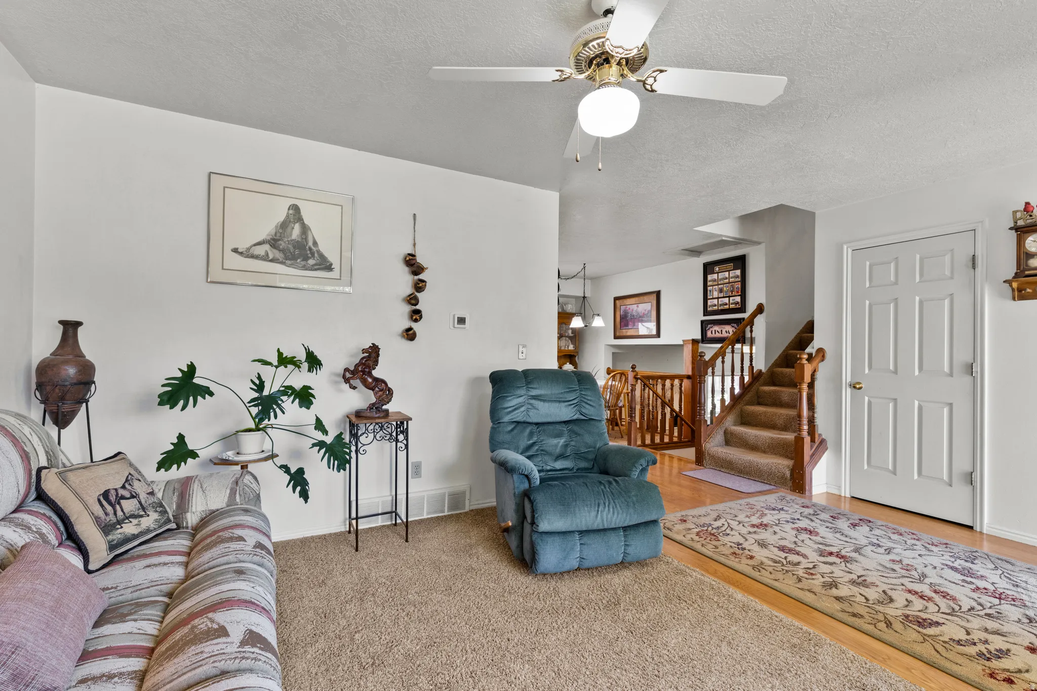 Spacious living area featuring a ceiling fan, light wood-finish flooring, and a six-panel interior door