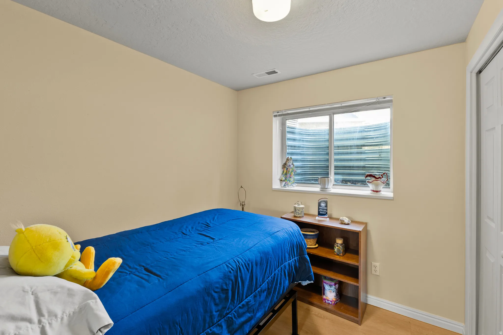 Bedroom featuring an egress window, light beige wall paint, white trim, and a built-in closet with a white door