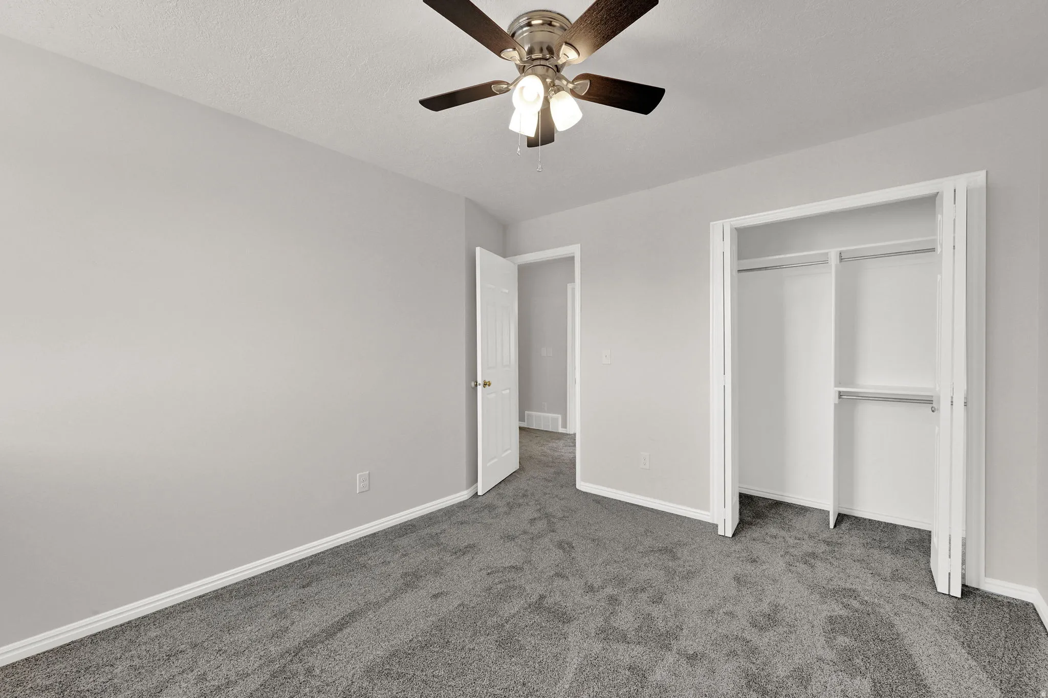 Neutral-toned bedroom featuring plush gray carpet, a ceiling fan with light fixture, and white painted walls