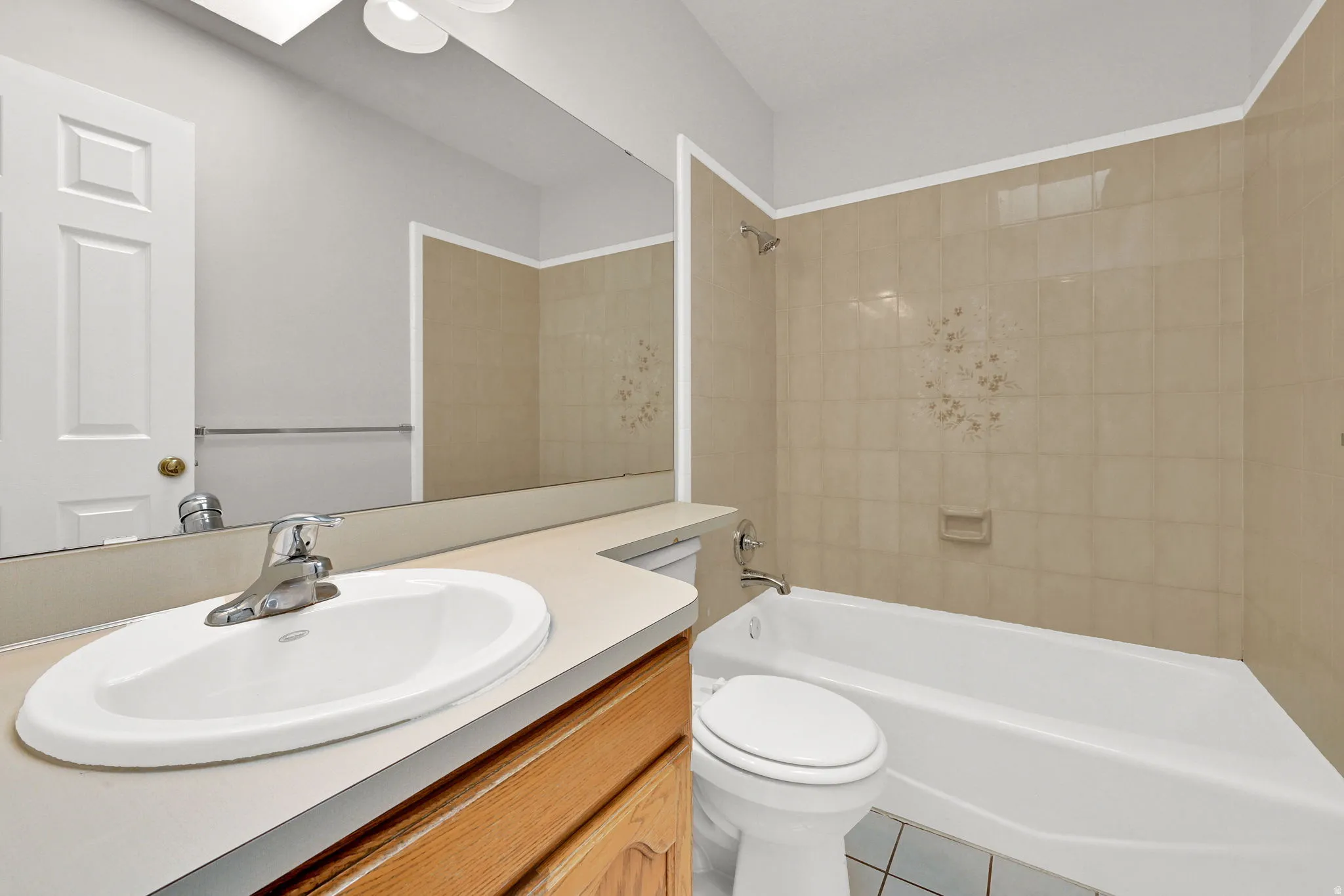 Full bathroom featuring a single vanity, integrated sink, chrome faucet, and wood-finish cabinetry
