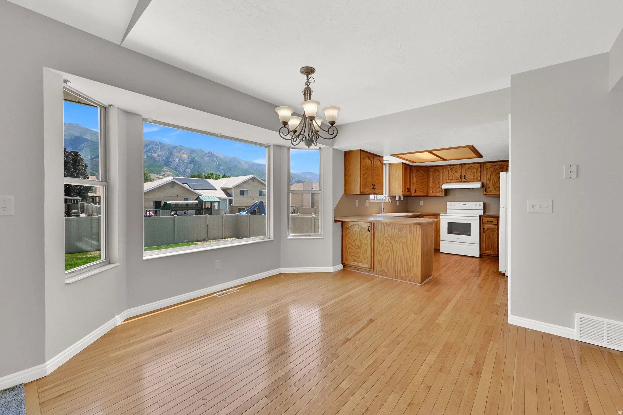 Dining area with wide bay windows, wood-finish flooring, and a multi-light chandelier
