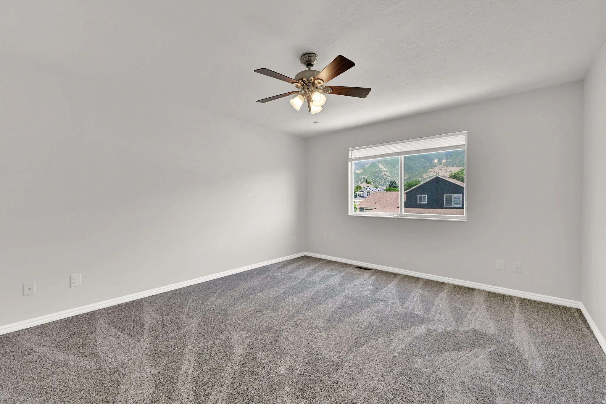 Bright room featuring neutral-toned walls and plush grey carpeting