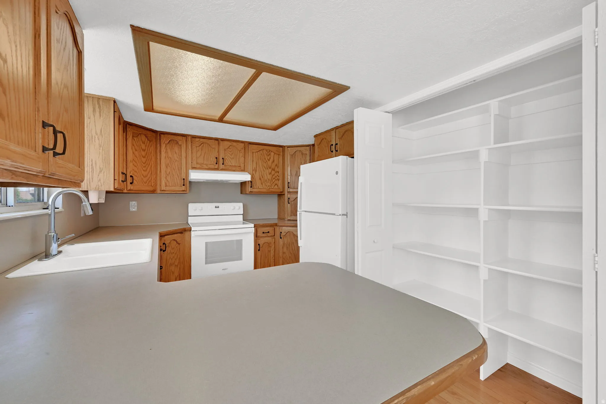 Kitchen featuring wood-finish cabinetry, white appliances, and a large built-in pantry with extensive shelving