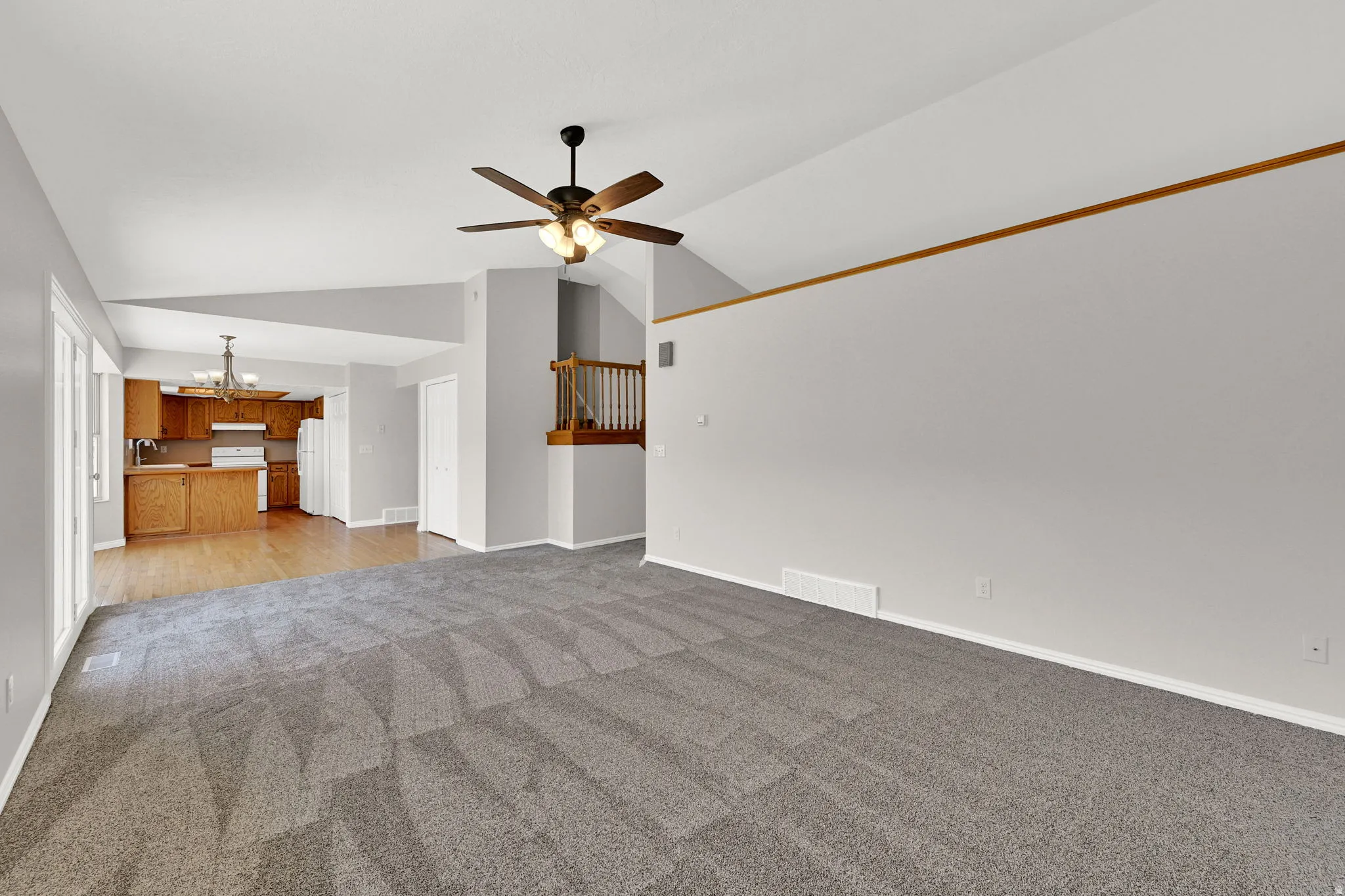 Spacious living area featuring vaulted ceilings and neutral gray carpeting