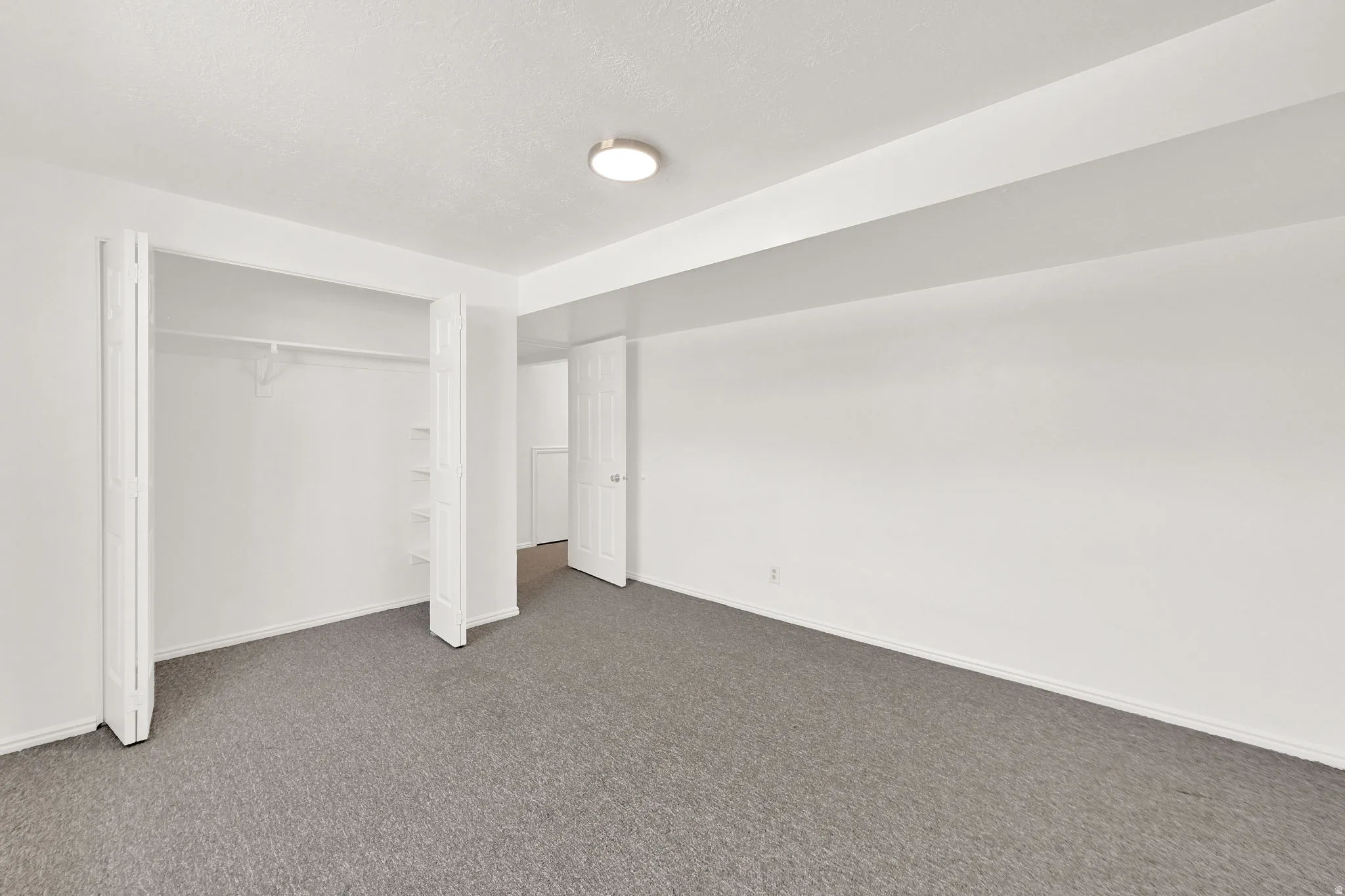 Spacious interior room featuring grey carpeting and white painted walls