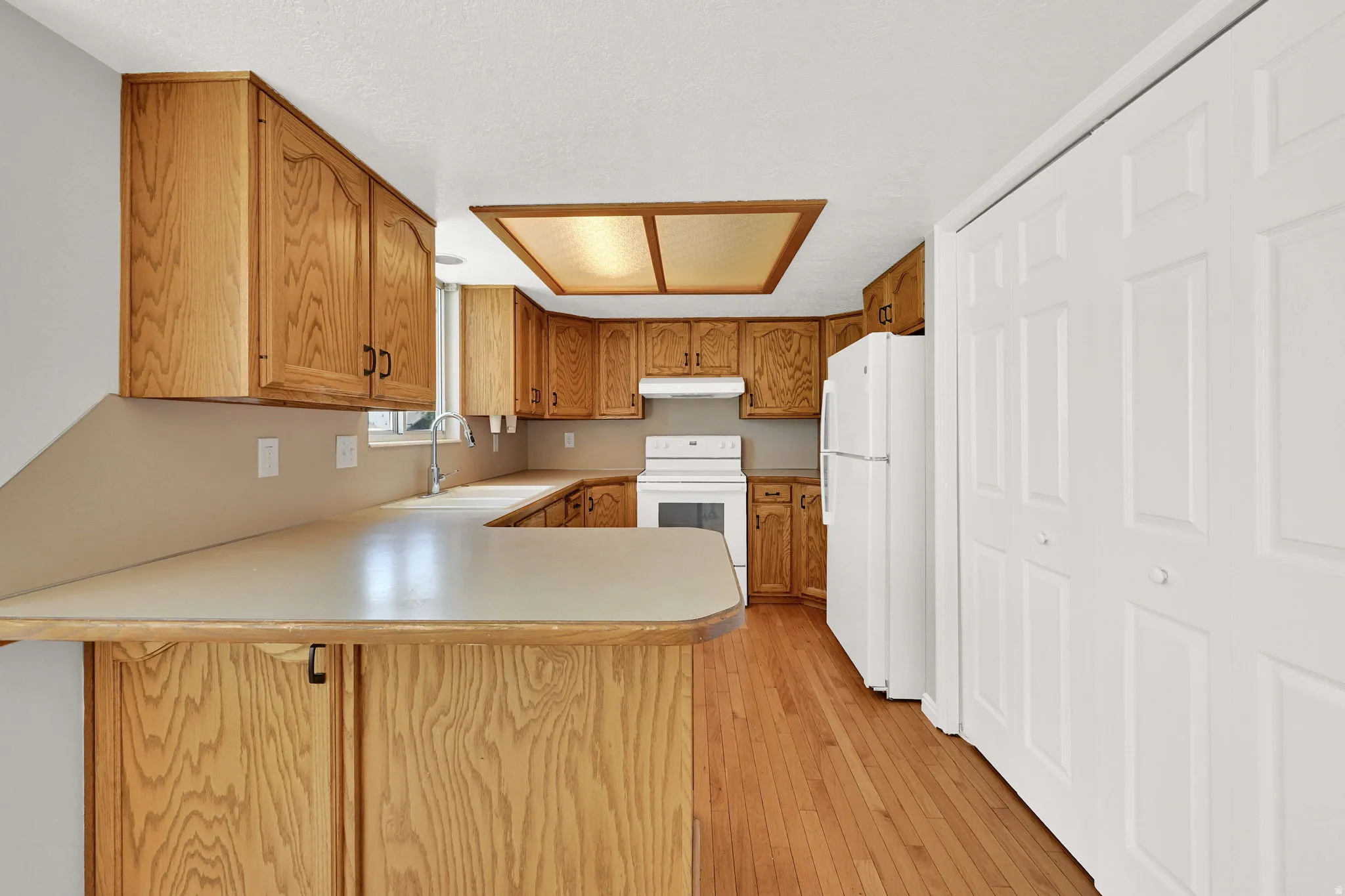 Kitchen featuring wood cabinetry, light countertops, and wood-finish flooring