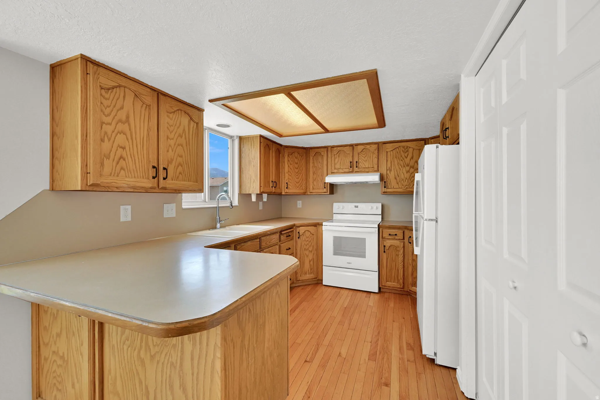 Functional kitchen with wood-finish cabinetry, solid surface countertops, and wood-finish flooring