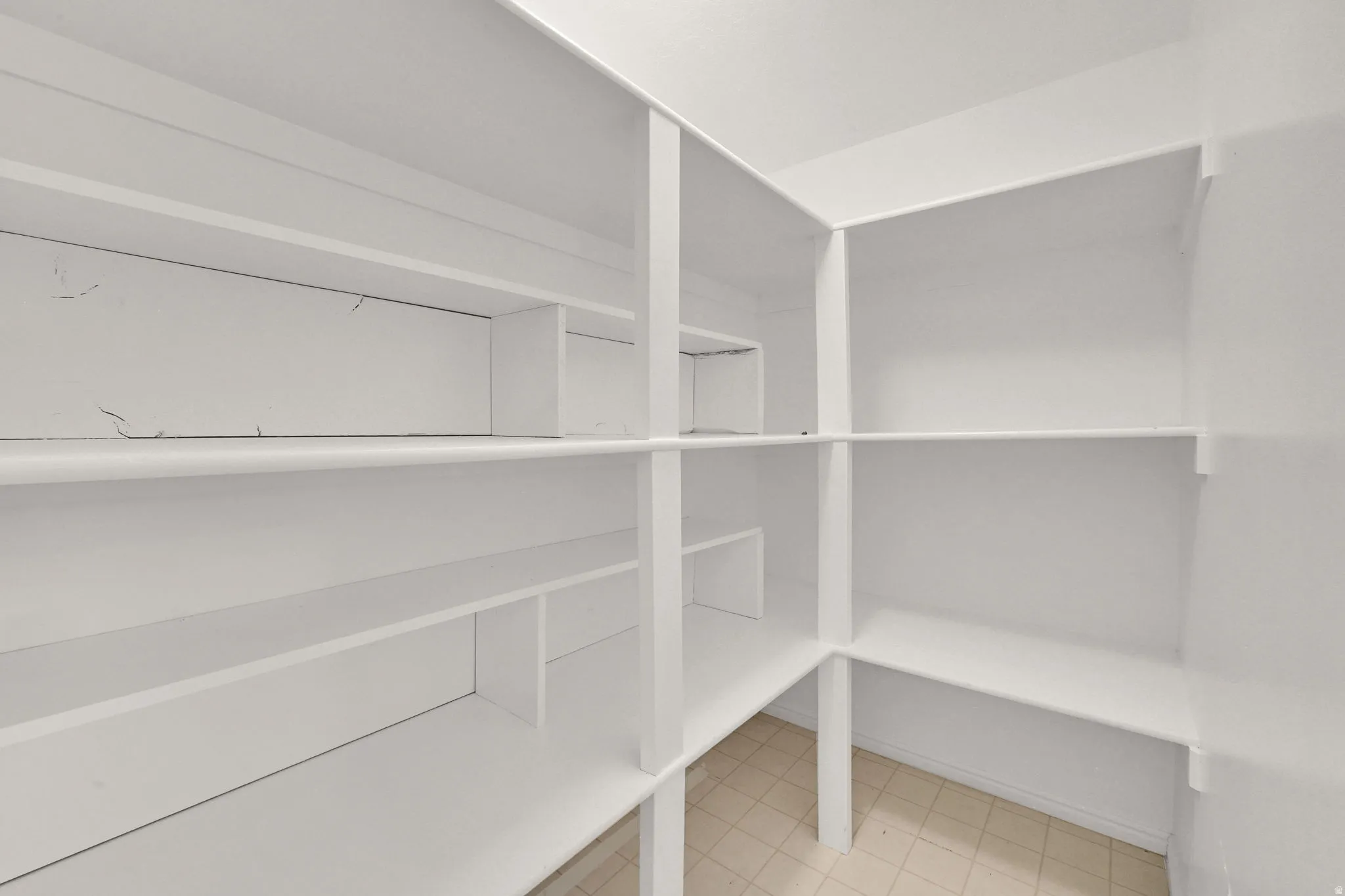 Built-in pantry shelving system with white painted finishes and tile flooring